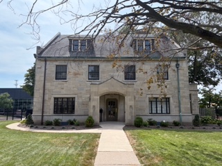 The Deanery's stone exterior on College Square, framed by trees, with a walkway to the arched front entrance